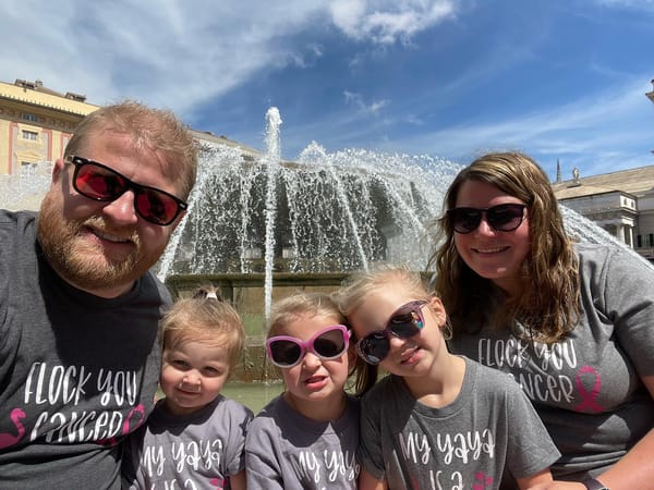 Family of five wearing "Flock You Cancer" shirts posing in front of fountain in Piazza de Ferrari, Genoa, Italy